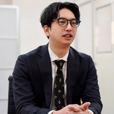 笑顔で話すスーツ姿の専務取締役 柴田 泰志
